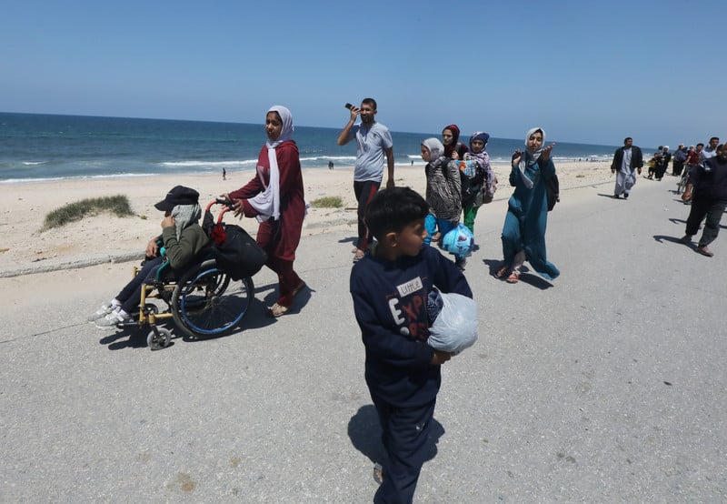 People wsalking along a sandy road carrying their belongings