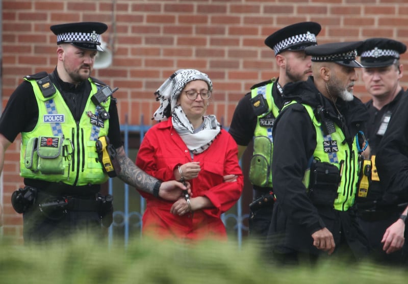 A woman in a Palestinian keffiyeh is arrested by British police