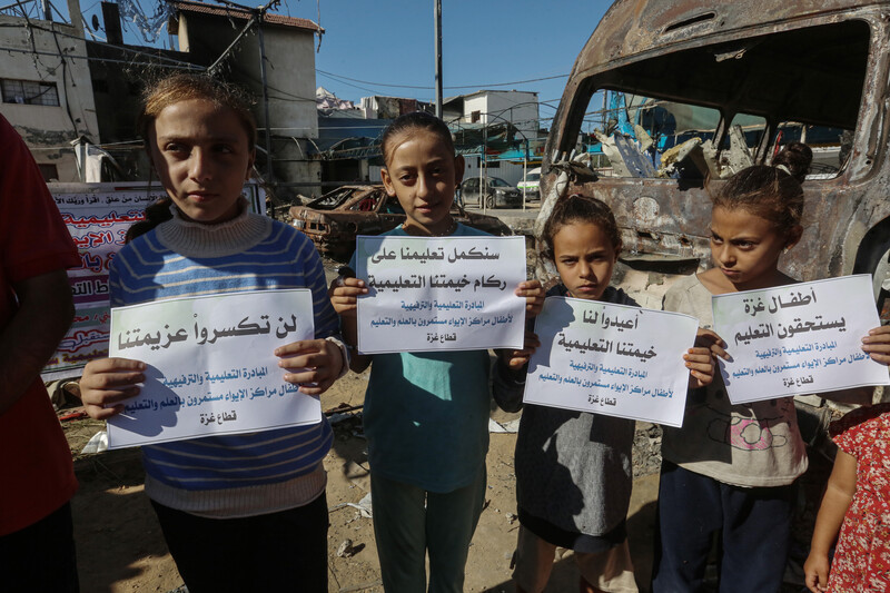 Children hold protest signs amid Israeli destruction in Deir al-Balah 