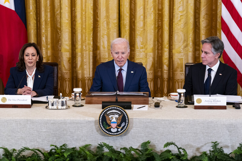 Kamala Harris, Joe Biden and Antony Blinken seated with flags behind them