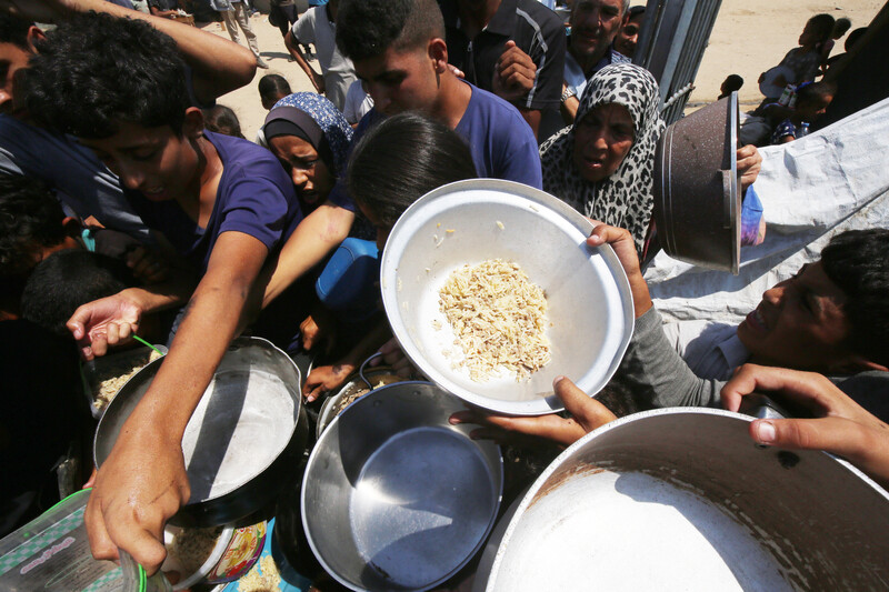 people crowd around a charity food distribution center for rice