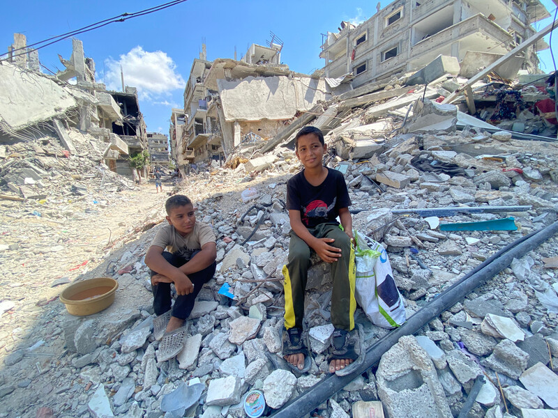 two boys sit on rubble