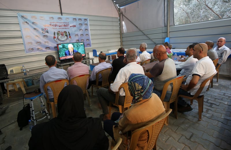 A group of people sit watching a monitor