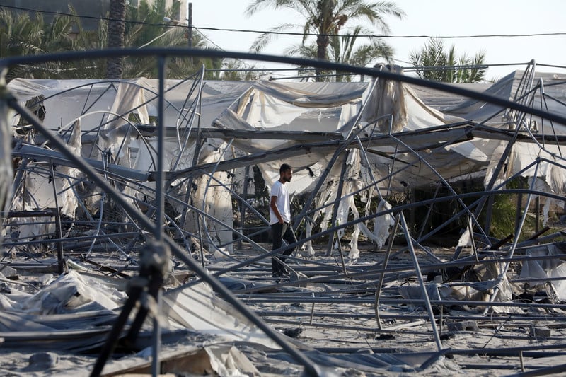 A man walks through the remains of burnt out tents