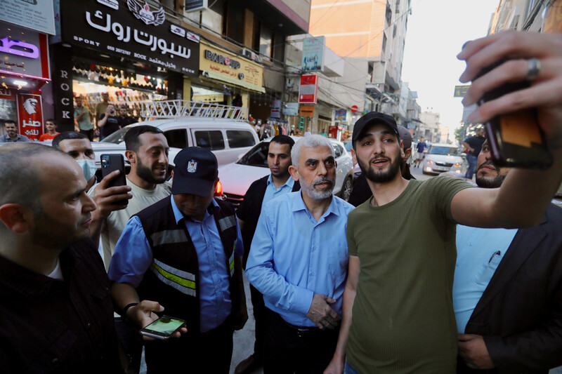 Yayha Sinwar surrounded by people in a street smiles for a selfie