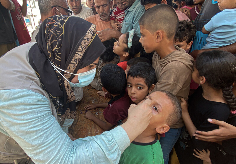 A woman administers a vaccine to a child