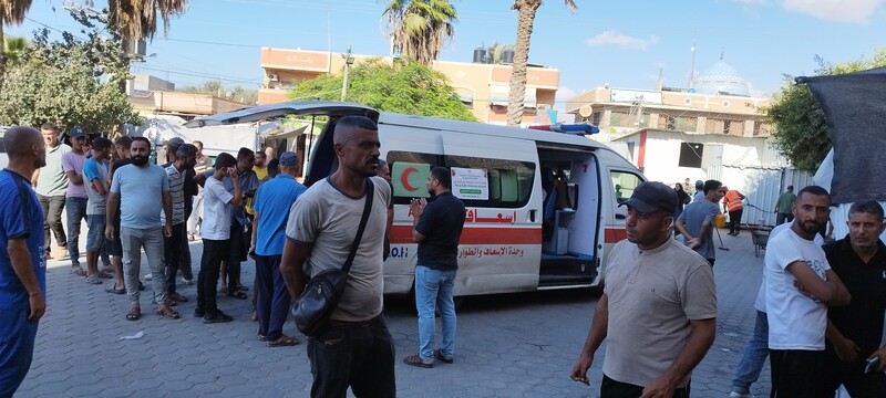 A man stands waiting with an ambulance behind him