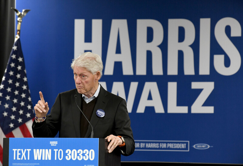 Former President Bill Clinton speaks in Milwaukee, Wisconsin in front of a Harris-Walz sign and an American flag