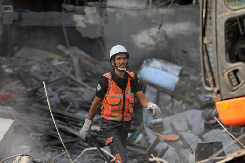 Un hombre con chaleco de alta visibilidad camina entre escombros.