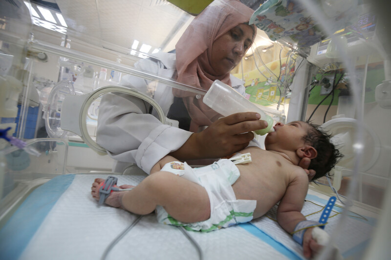 A baby is being fed milk inside an incubator