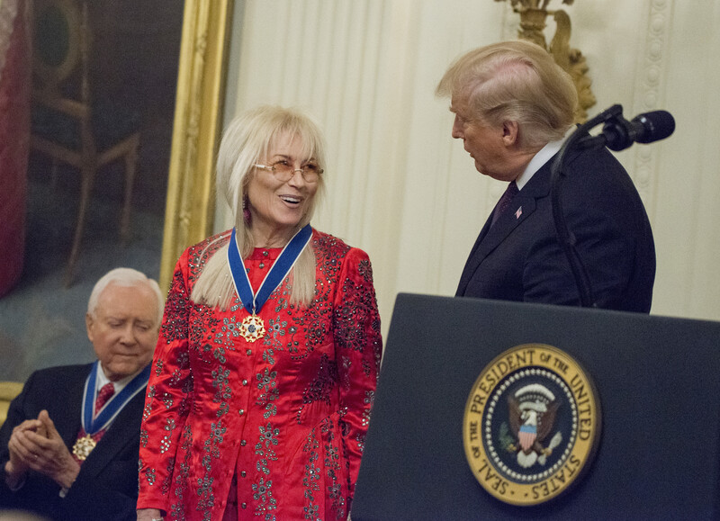 President Donald Trump at podium in East Room of White House with Miriam Adelson and Senator Orrin Hatch