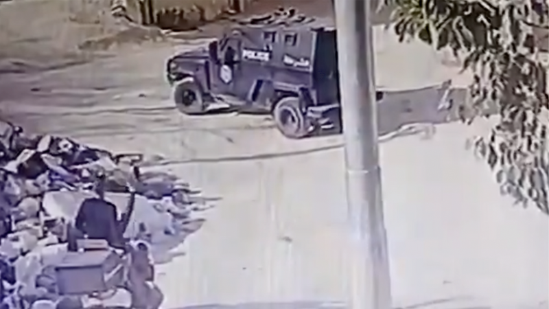 Two teens on a motorcycle parked feet away from armored vehicle 