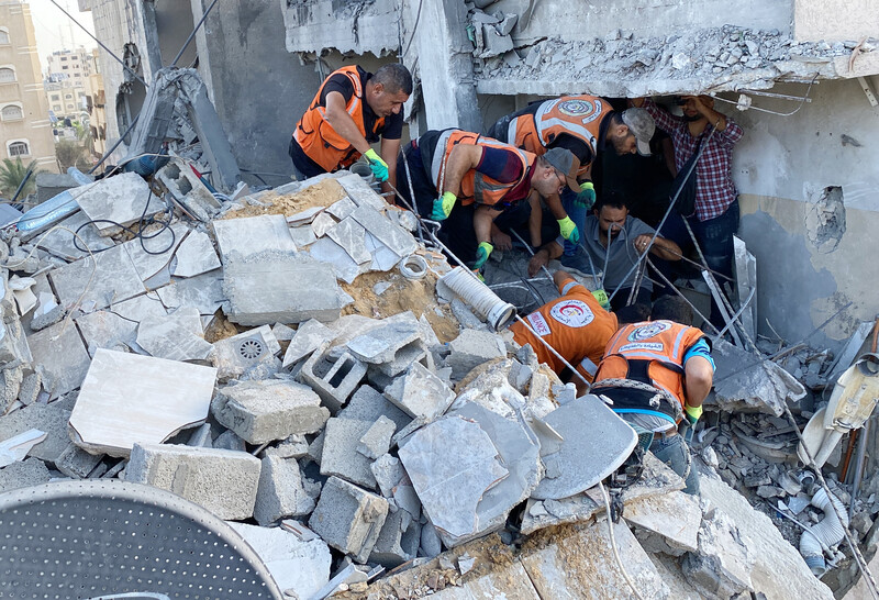 Emergency workers look through the rubble of a house