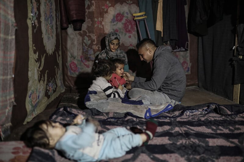 a family huddles together in their tent 