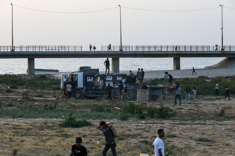 people carry goods away from a truck