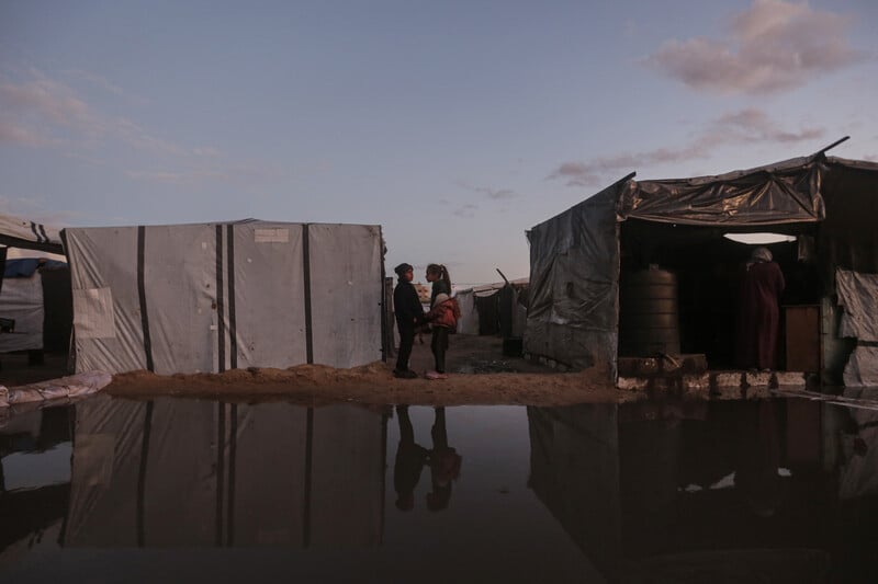 a large puddle lies between two tents