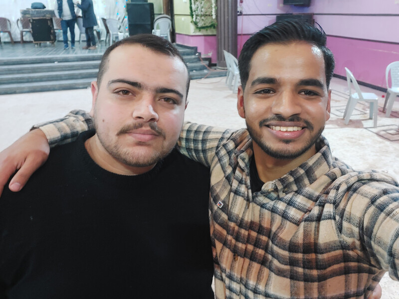 Selfie of two young men embracing while standing in wedding hall