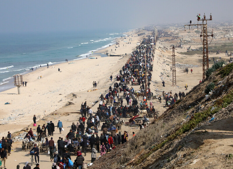 Thousands of people walk along a beach