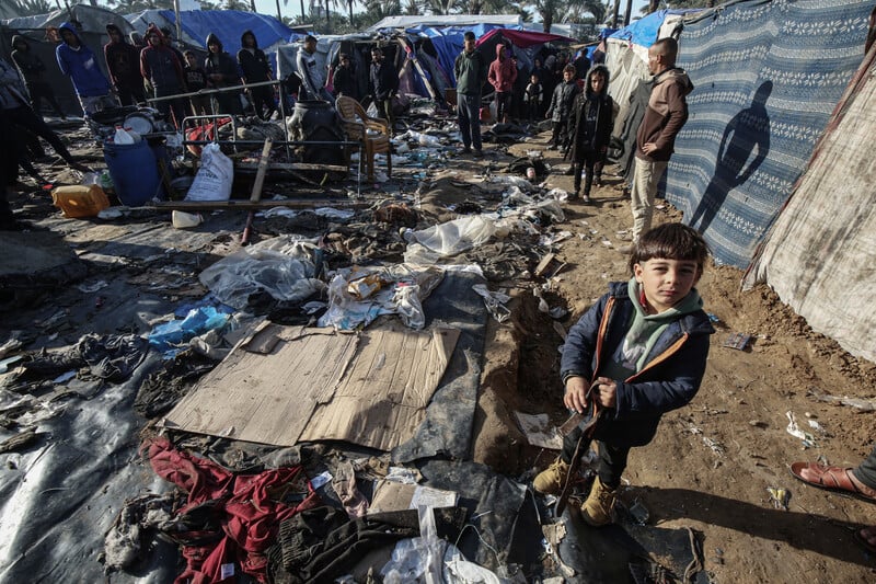 A boy stands next to a destroyed tent