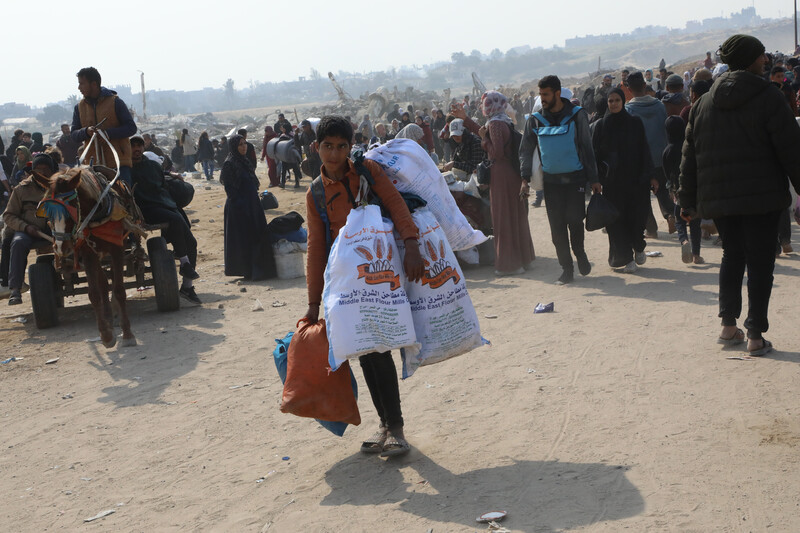 A child with heavy bags amid a crowd of people on foot
