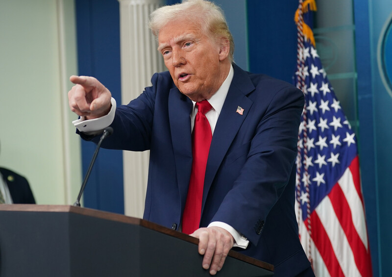 President Donald Trump points from podium with American flag behind him