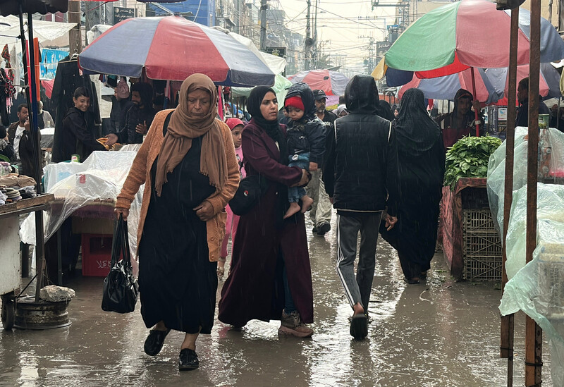 People walk through a market in the rain