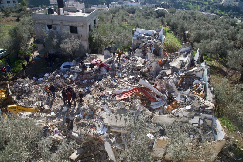 People inspect the rubble of a house where two Palestinians were killed during an Israeli raid in Burqin village near Jenin, 23 January.