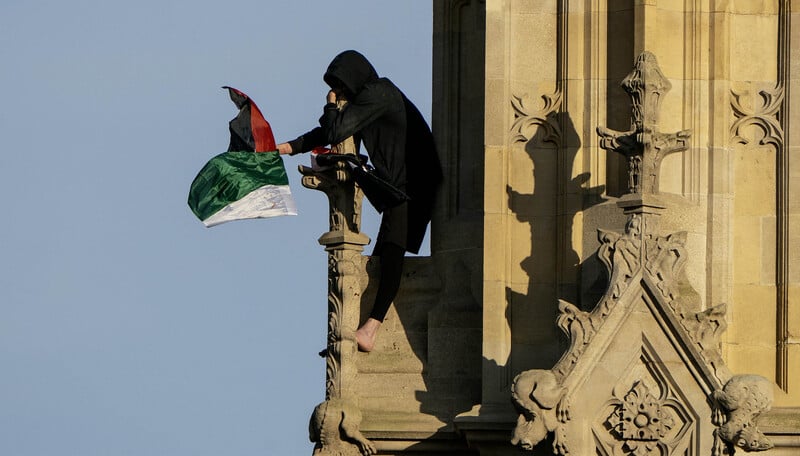 A man waves the Palestinian flag from a perch on Big Ben