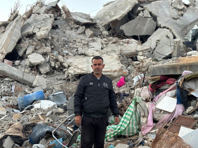 A man stands before a destroyed building