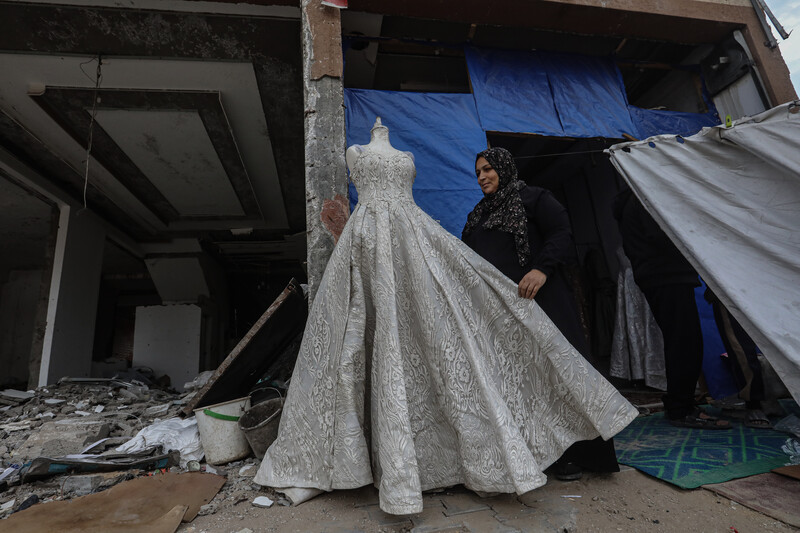 A woman stand next to a mannequin wearing a wedding dress