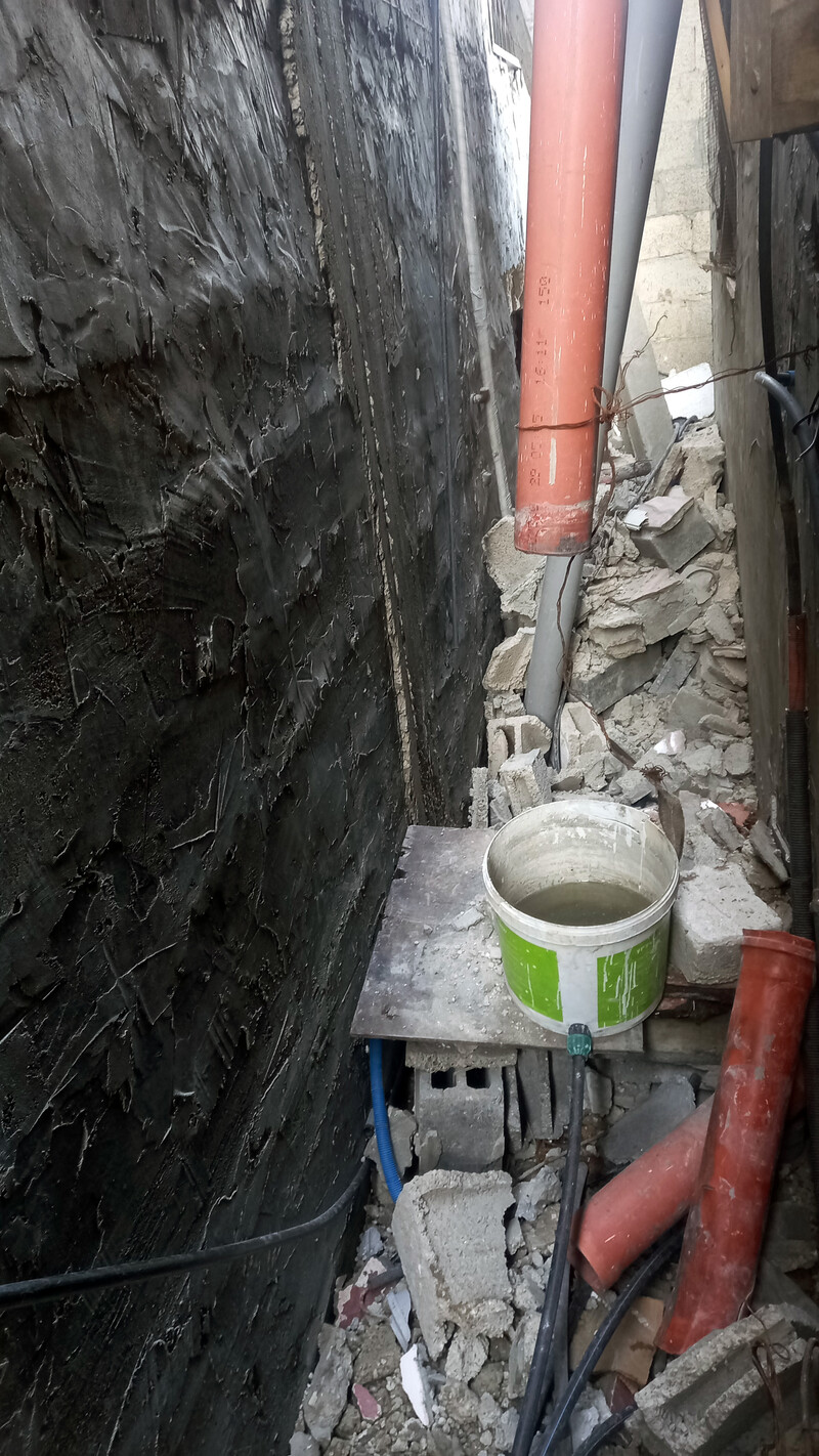 A 5-gallon bucket sits underneath a PVC pipe in a narrow gangway