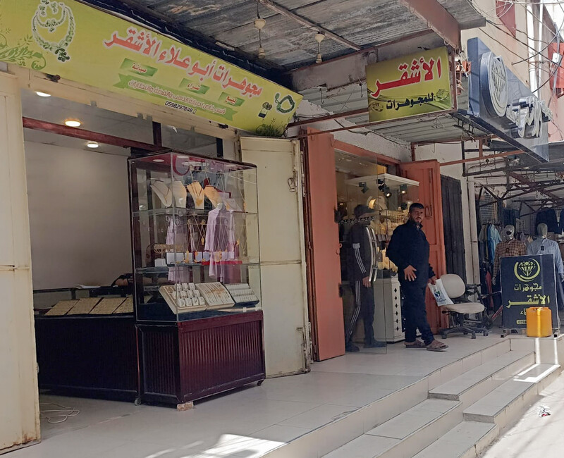 A man holds a plastic bag while standing in front of a jewelry shop