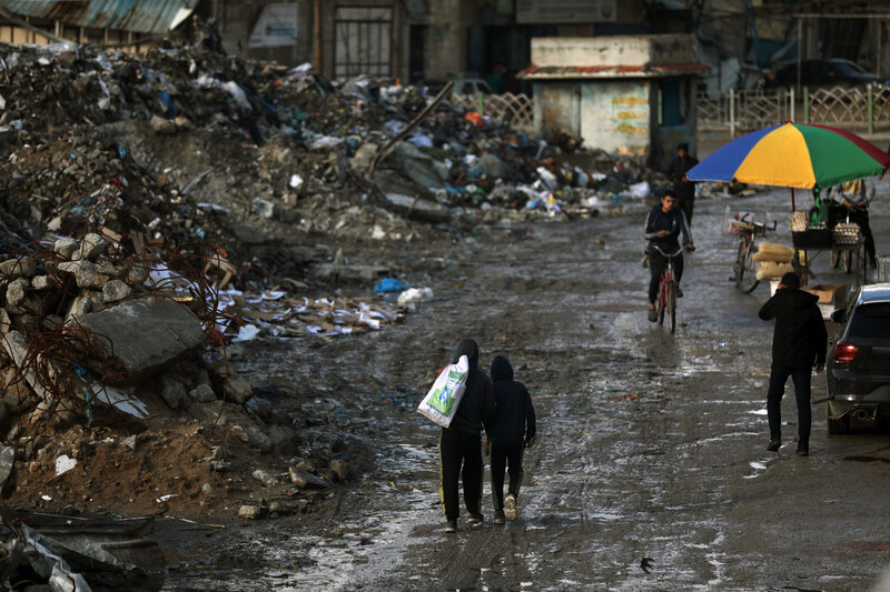 People walk past mountains of waste in Gaza