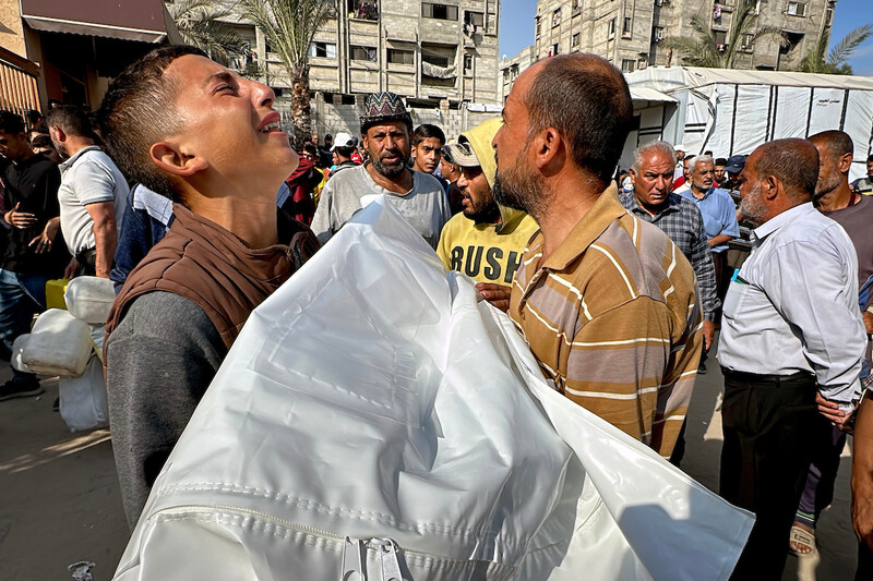 A group of men hold a body wrapped in a shroud. One of the men is weeping.
