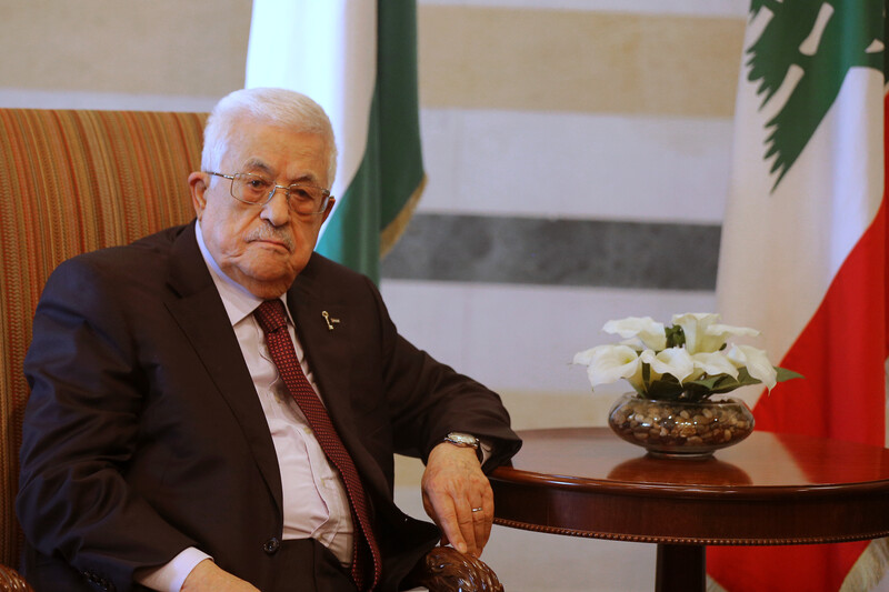 Mahmoud Abbas sits at a table next to some flowers
