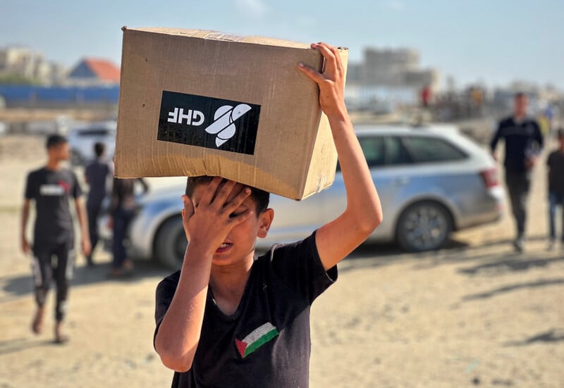 A boy carries a box as he and others seek aid 