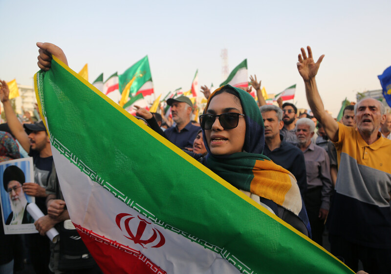 Woman surrounded by people holds Iranian flag