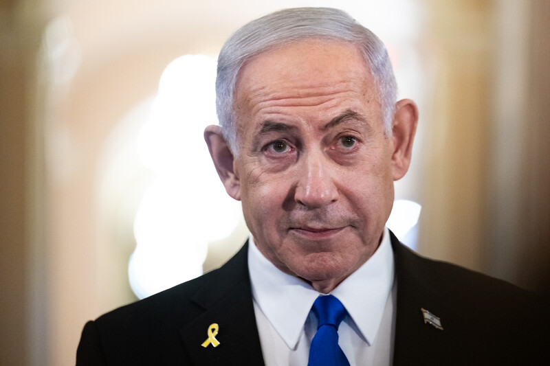 Israeli Prime Minister Benjamin Netanyahu stands with a yellow ribbon and Israeli flag lapel pin on his suit jacket