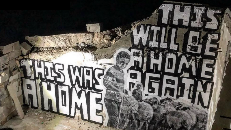 Graffiti reading: This was a home. This will be a home again