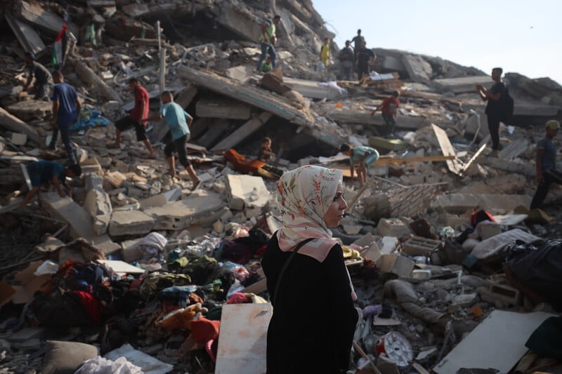 A woman walks past the rubble of a bombed tower block
