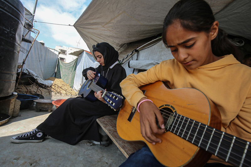 Two girls play guitar