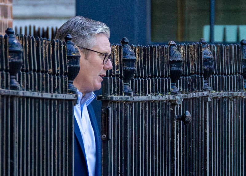 UK Prime Minister emerges from a metal fence