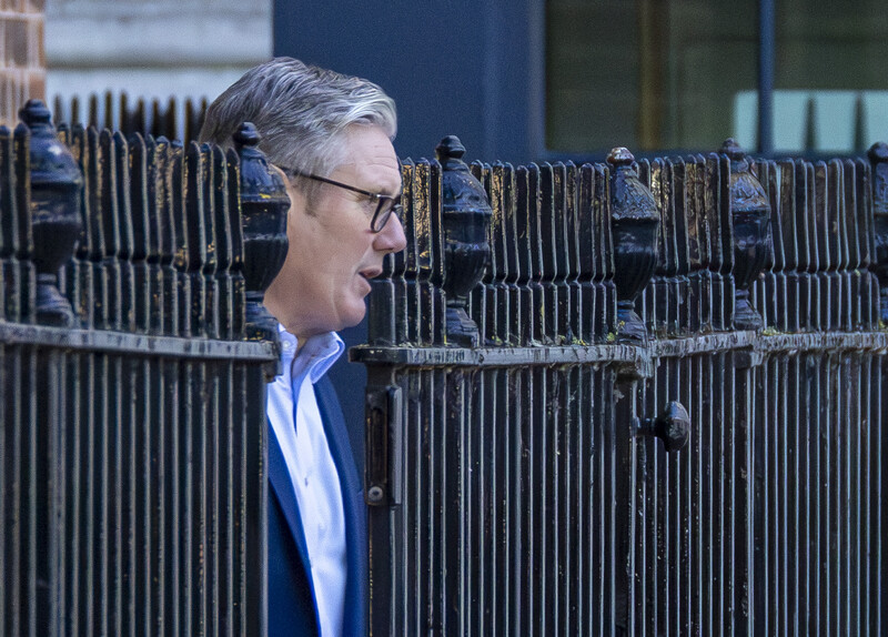 UK Prime Minister emerges from a metal fence