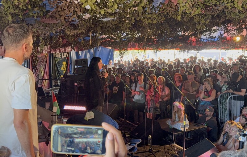 A woman speaks to a crowded tent