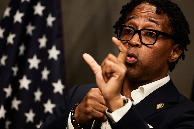 Congressman Wesley Bell gesticulates with an American flag near him