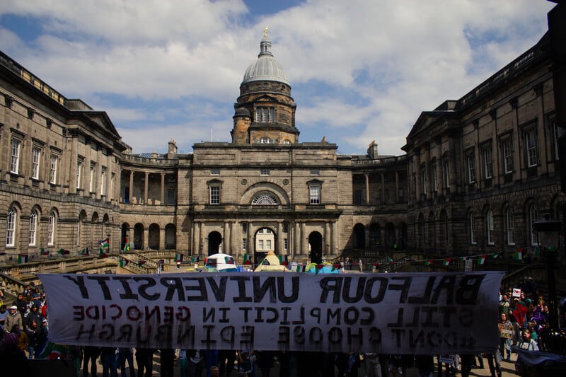Protest at University of Edinburgh with a banner seen from the back emblazoned with "Balfour's University"