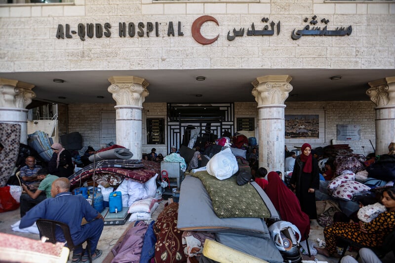 displaced people and their belongings in front of a hospital entrance