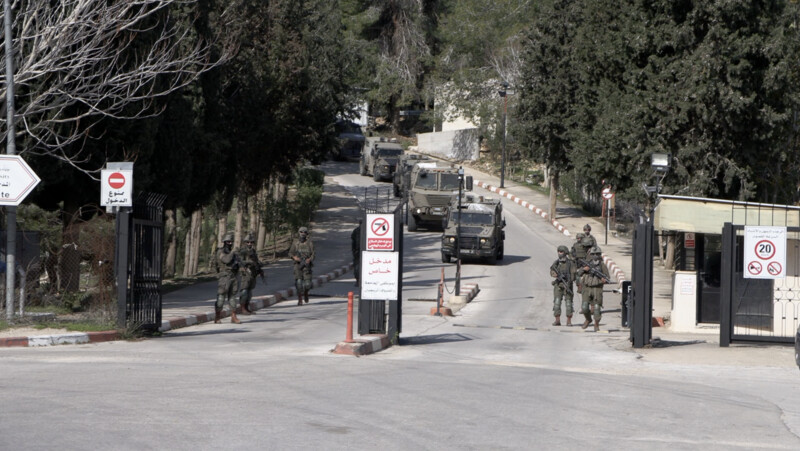 Soldiers and military vehicles move up a road