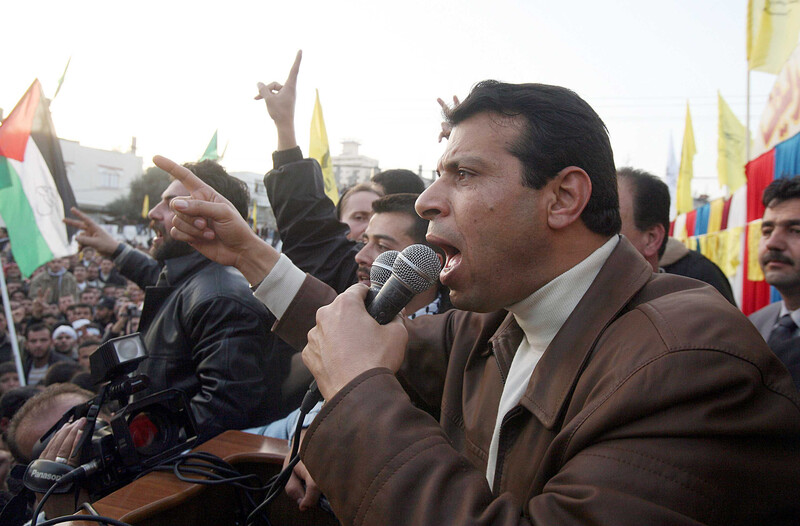 Muhammad Dahlan holds two microphones while raising his pointer finger in the air
