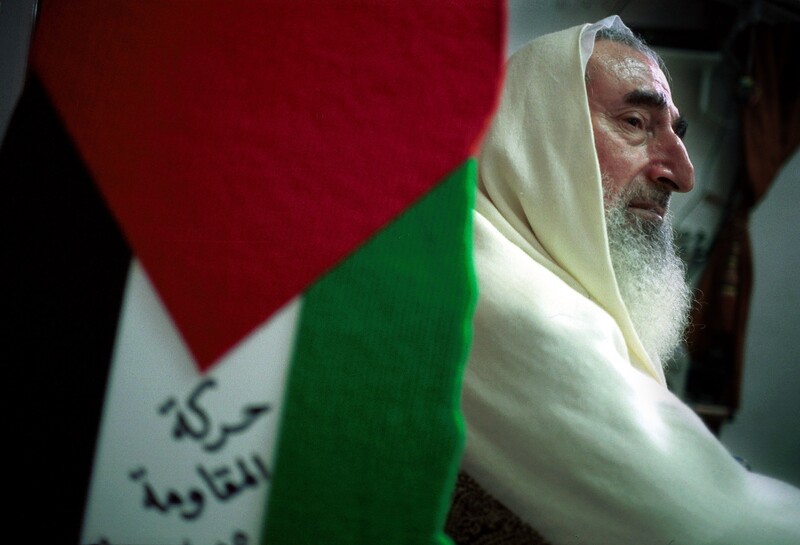Profile of Ahmad Yassin sitting next to a Palestine flag
